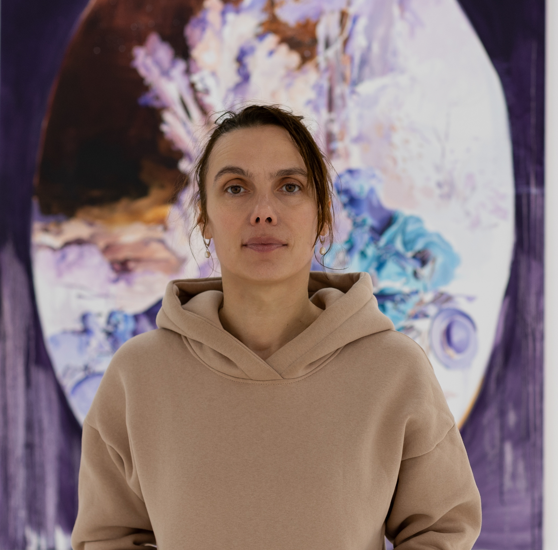 Anna Orbaczewska – malarka w swojej pracowni artystycznej, siedzi przed olejnymi płótnami